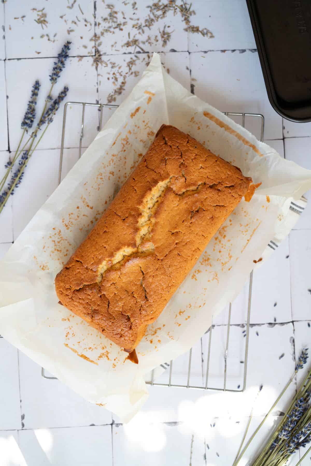 Delicious homemade banana bread loaf cooling on a wire rack with lavender sprigs nearby.