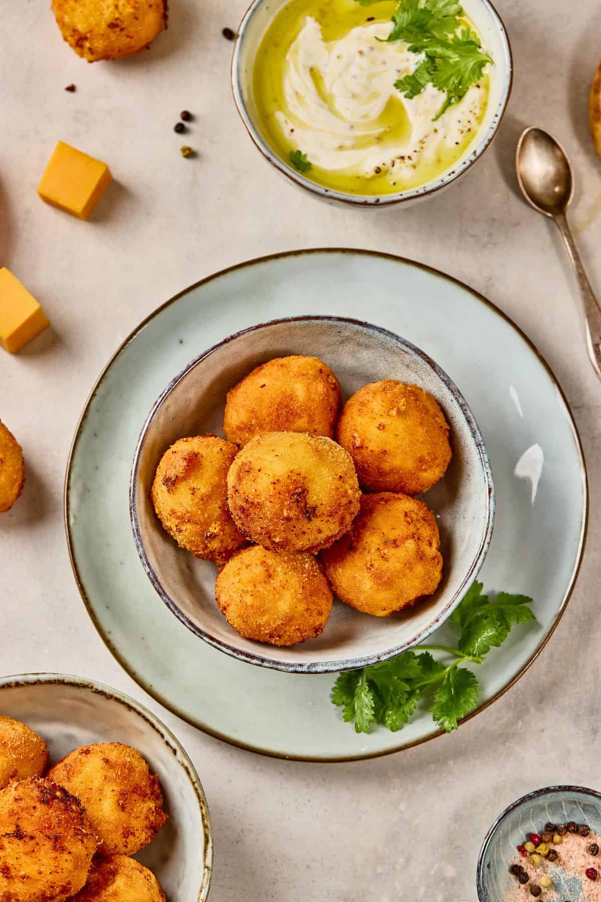 Crispy golden croquettes served with creamy dip and fresh cilantro.