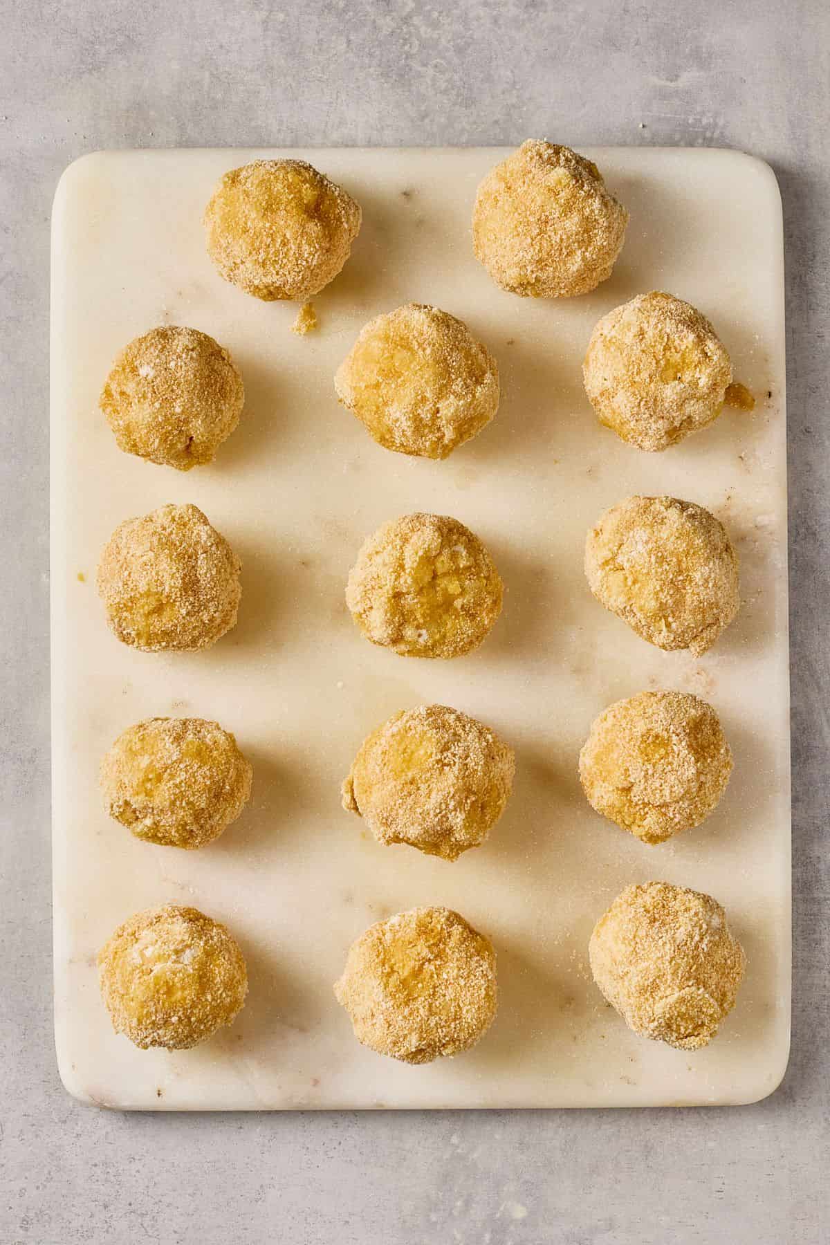 Delicious homemade croquettes arranged on a white cutting board for baking or frying.