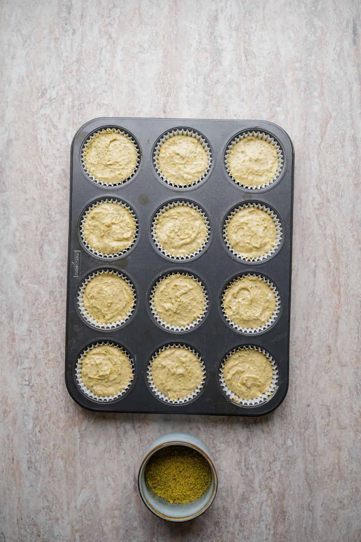 Delicious cupcake batter in a muffin tin, ready for baking on a light-colored surface.