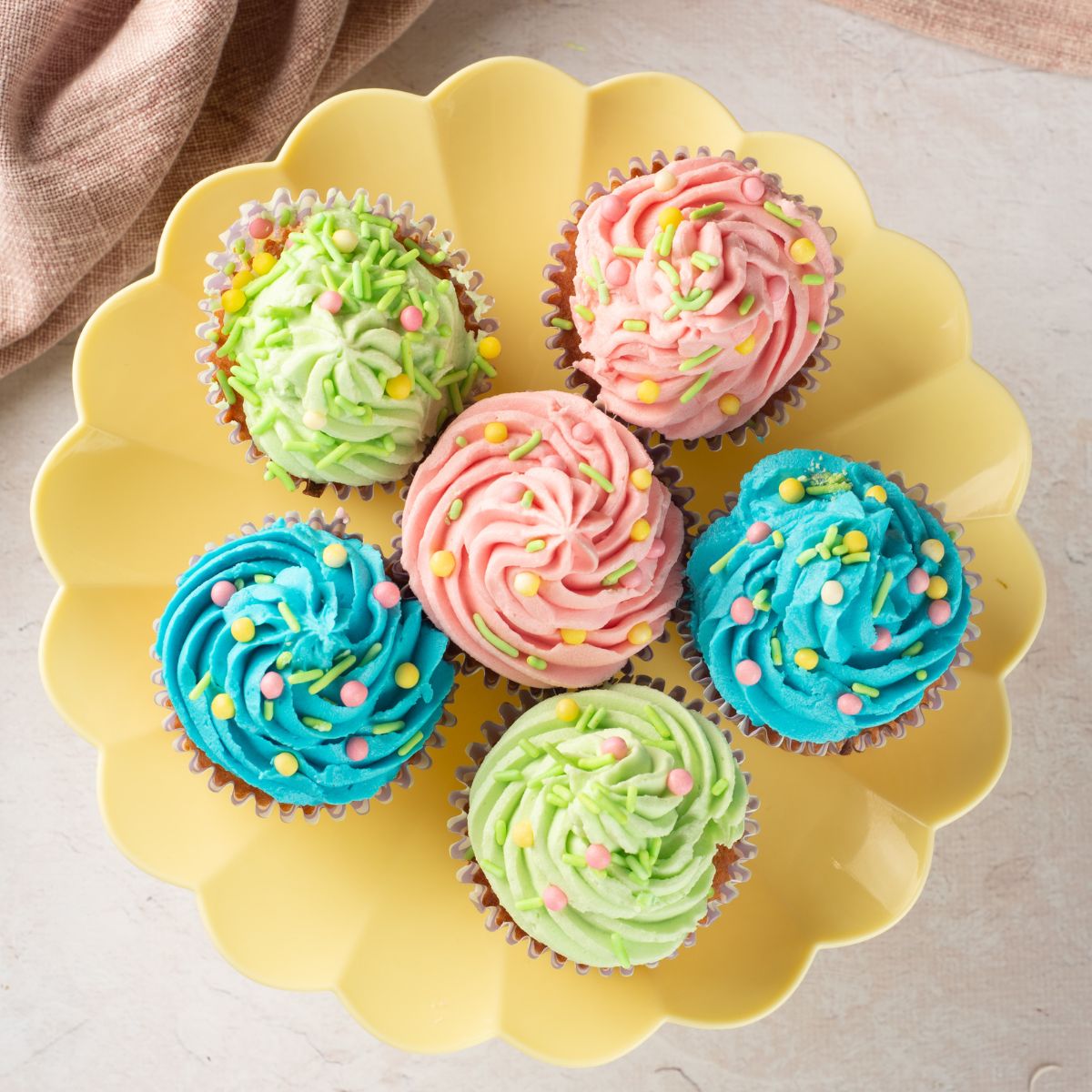 Bright, fun cupcakes decorated with pink, green, and blue frosting and colorful sprinkles.