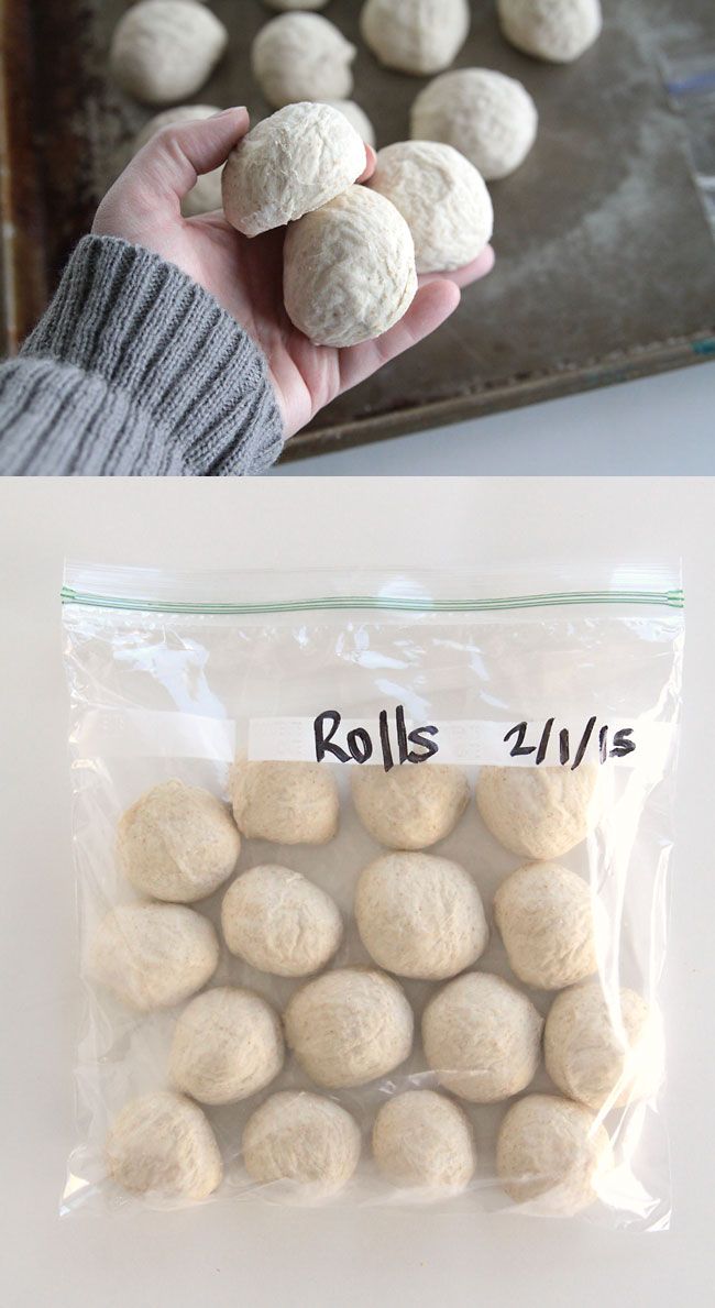 A hand holding several raw dough balls, with more on a baking sheet.