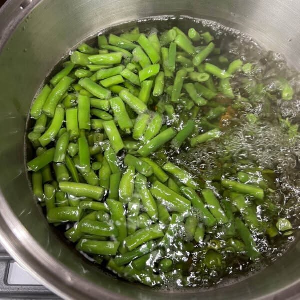 Green beans boiling in a metal pot on a stovetop