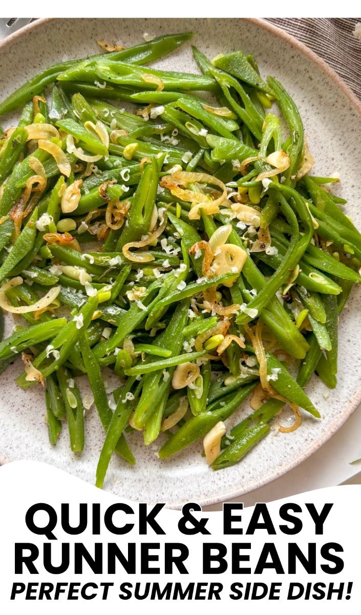 Runner beans topped with caramelized onions, sliced garlic, and white specks on a light-colored plate.