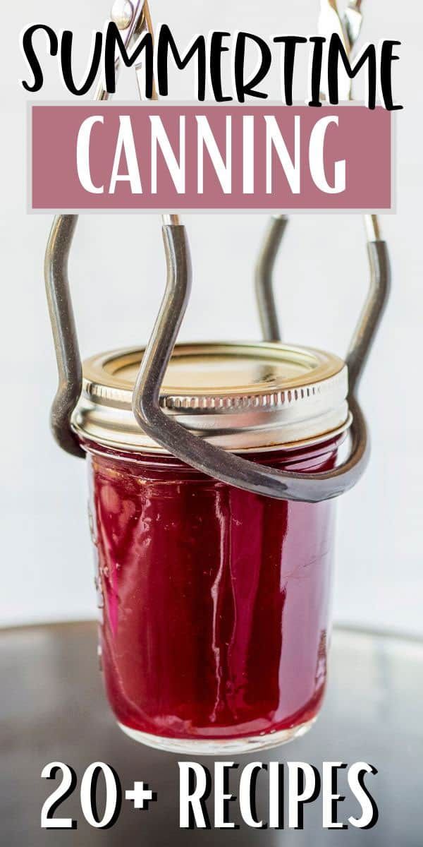 A canning jar filled with red preserve, held by a metal jar lifter.