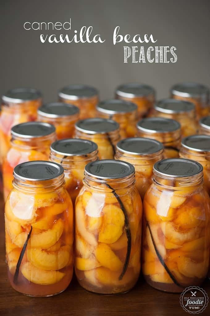 Rows of glass jars filled with sliced peaches and whole vanilla beans, sealed with metal lids.