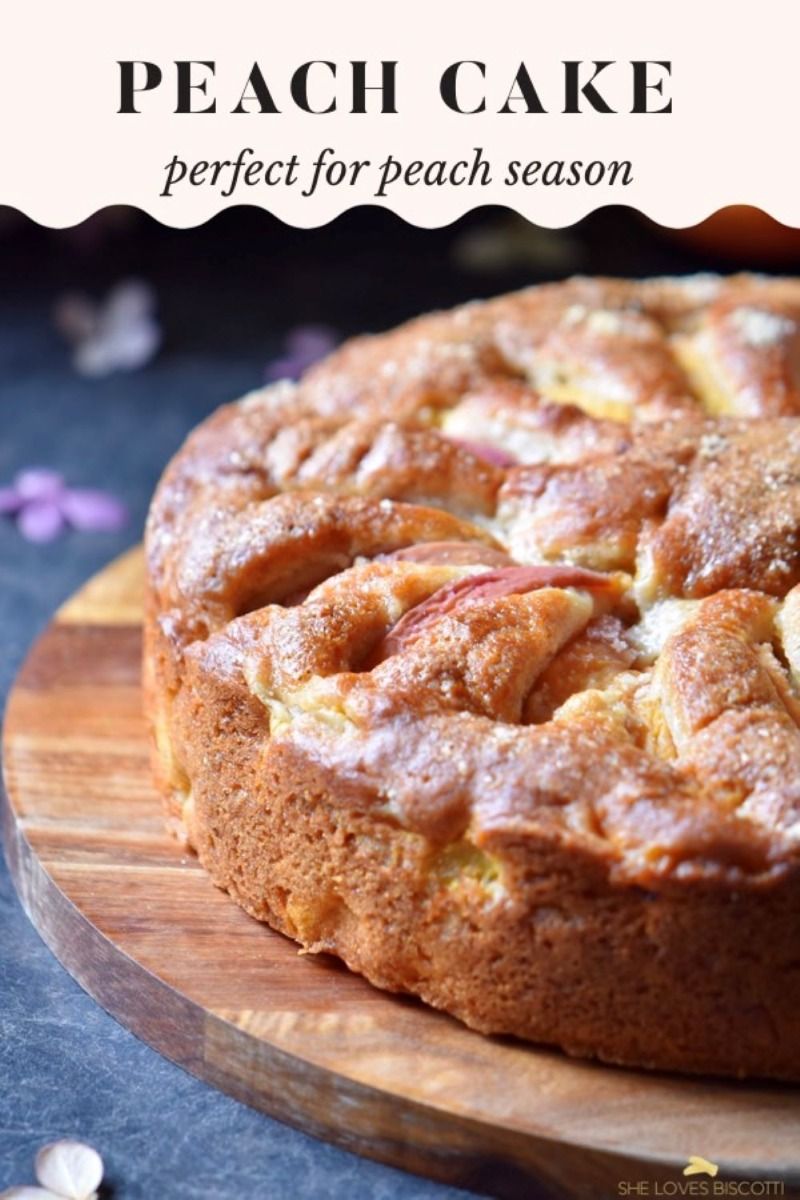 Round peach cake on a wooden cutting board with a textured surface, ready to be sliced
