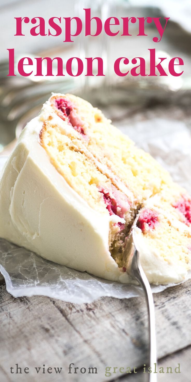 A slice of white frosted layer cake, revealing yellow cake with raspberry filling between layers, a fork resting in the…