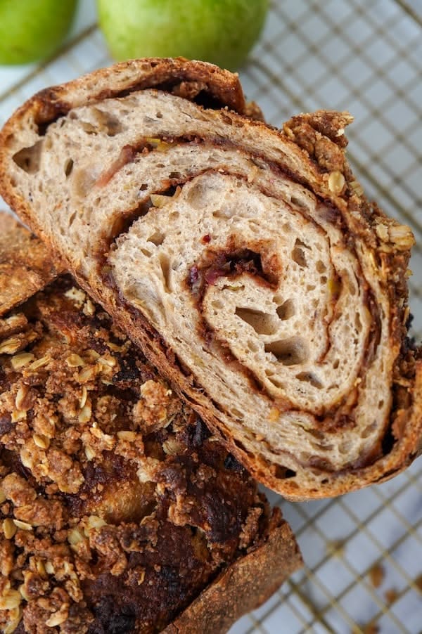 Sourdough bread sliced open, revealing a cinnamon swirl and apple crisp topping