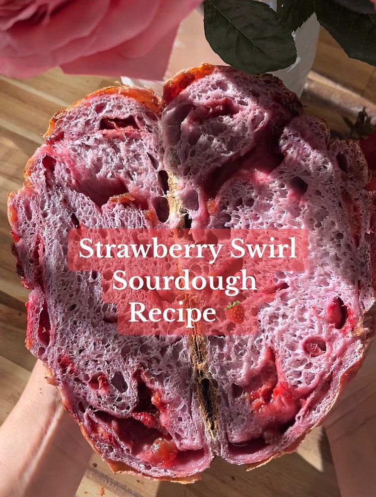Close-up of a sliced strawberry swirl sourdough loaf, revealing pink crumb with red fruit filling.