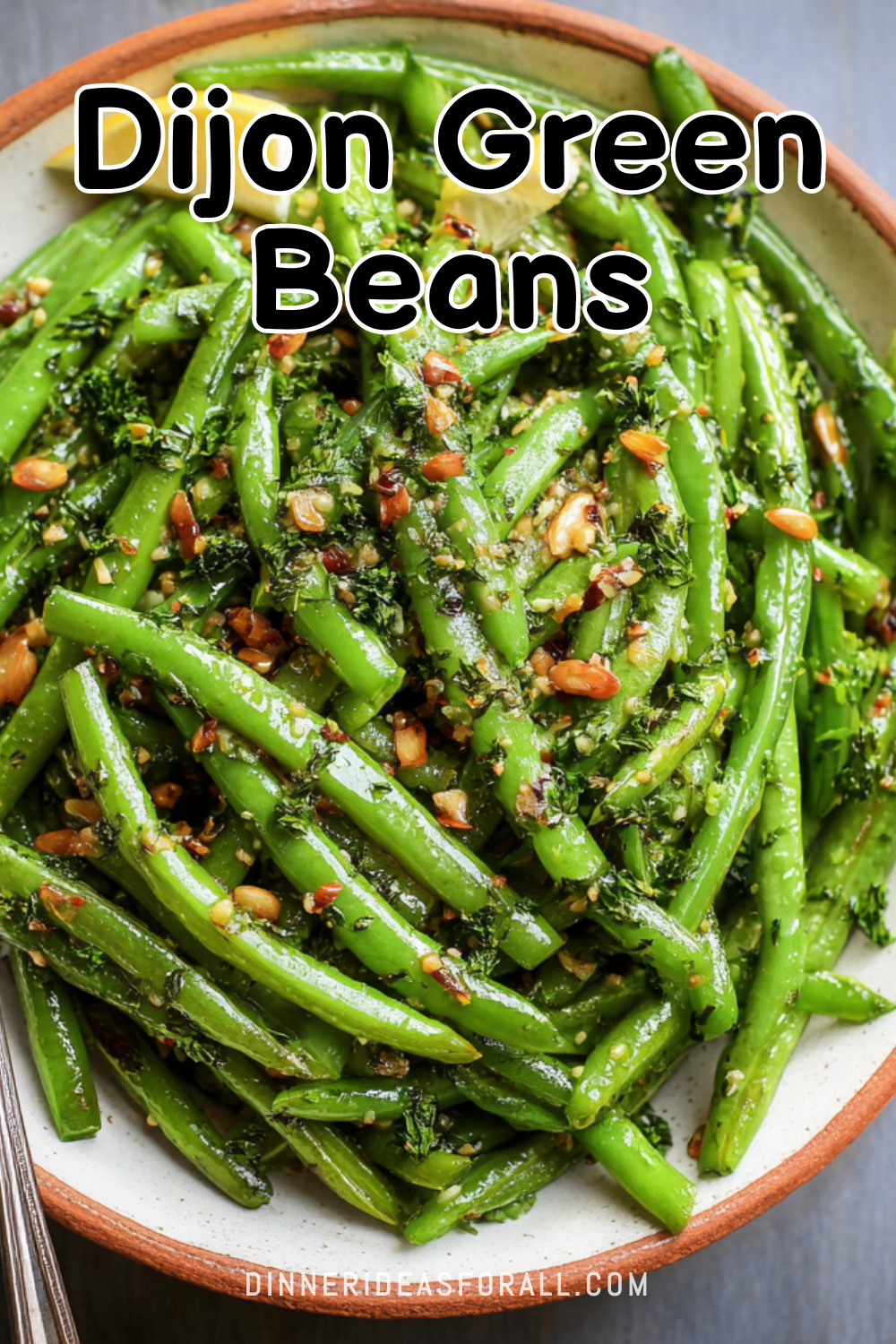 Close-up of baked green beans coated in a Dijon mustard sauce, garnished with herbs and chopped nuts.