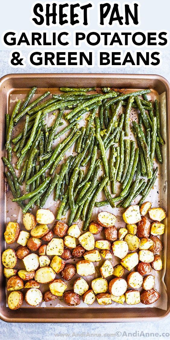Garlic green beans and diced potatoes roasted on a sheet pan lined with parchment paper.
