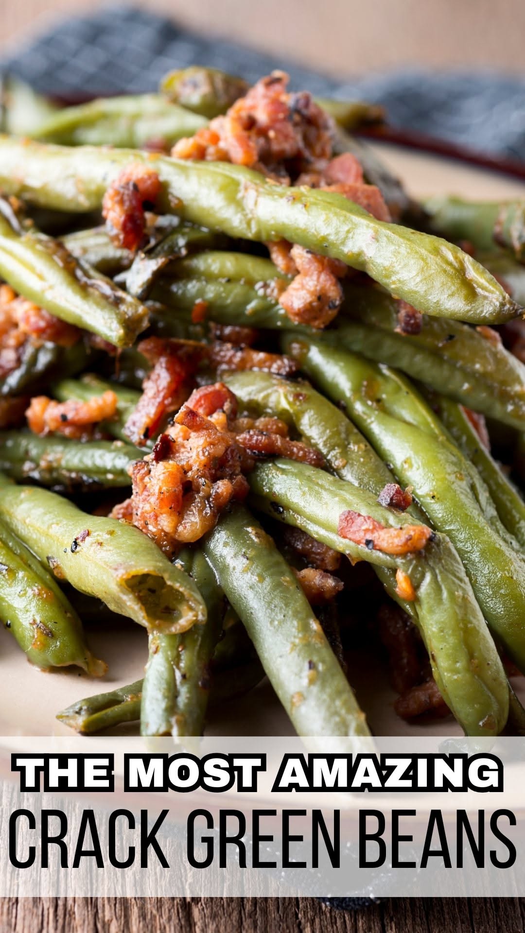 Close-up of baked green beans generously topped with crumbled bacon bits, on a light-colored plate.