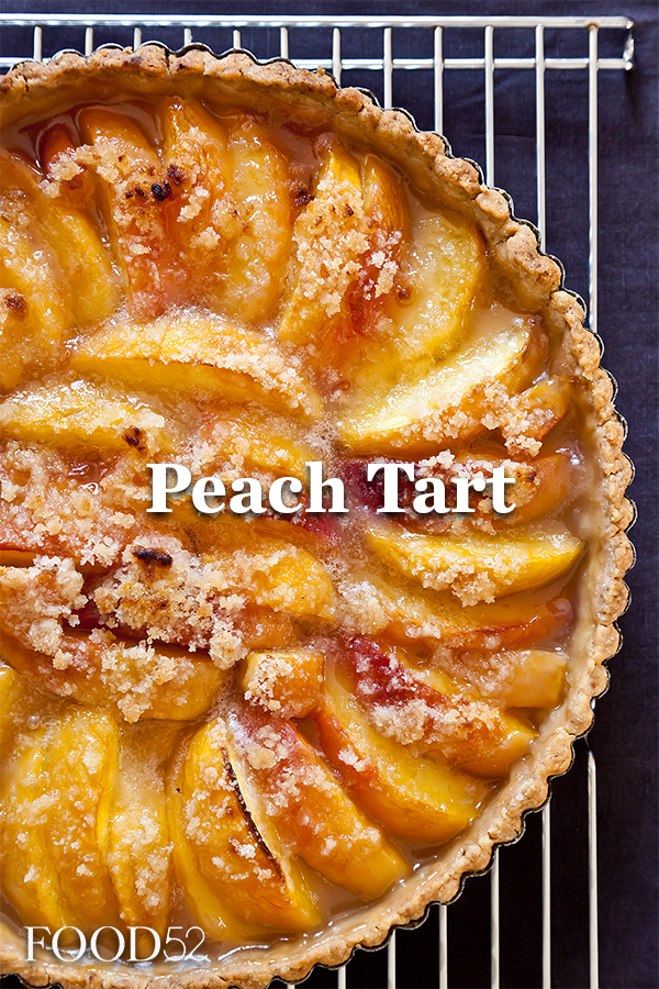 Close up of a baked peach tart with a crumb topping cooling on a wire rack