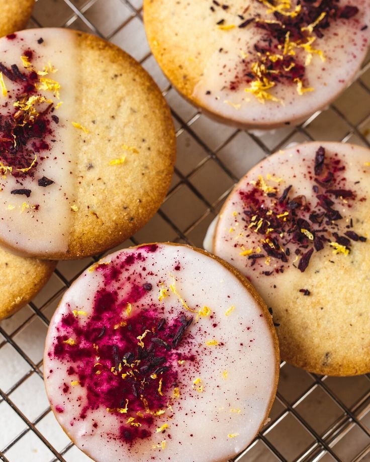Close-up of round sugar cookies with white icing, sprinkled with red flakes and yellow zest.