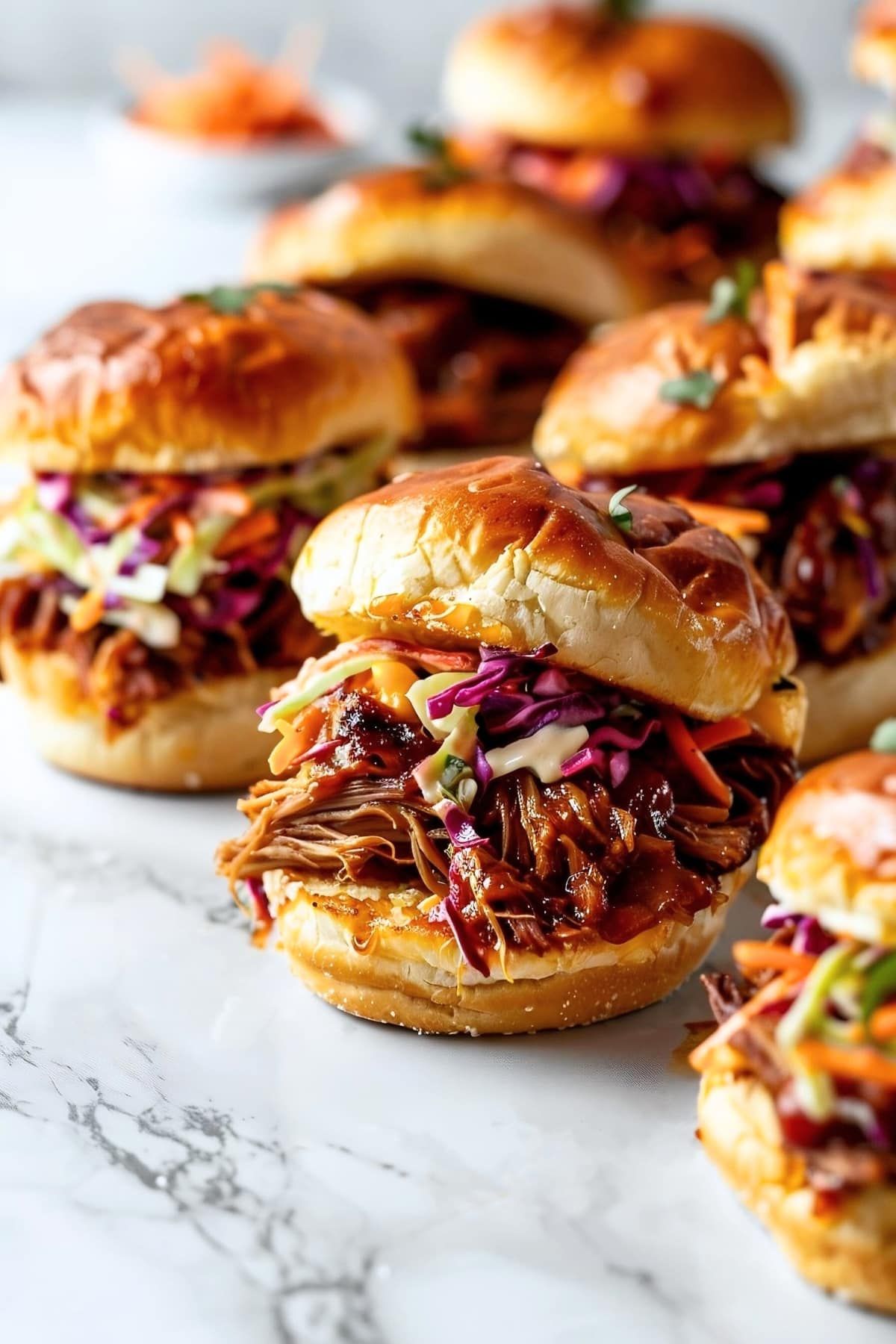 Many pulled pork sliders with coleslaw on sweet rolls