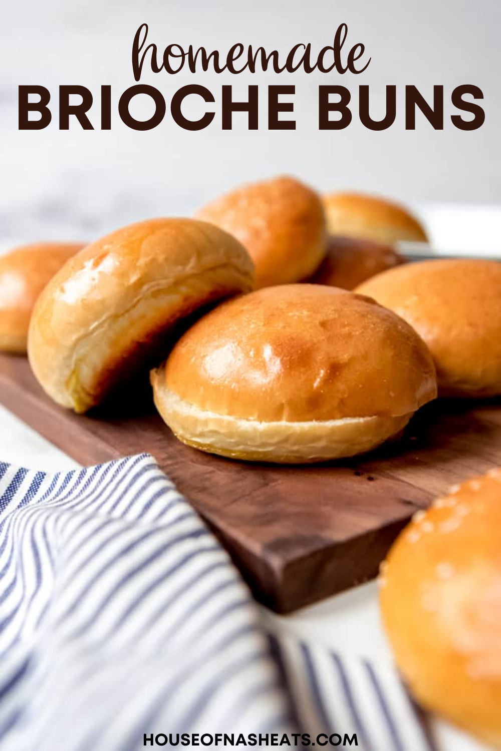 Close-up of golden brown brioche buns on a wooden cutting board with a striped linen