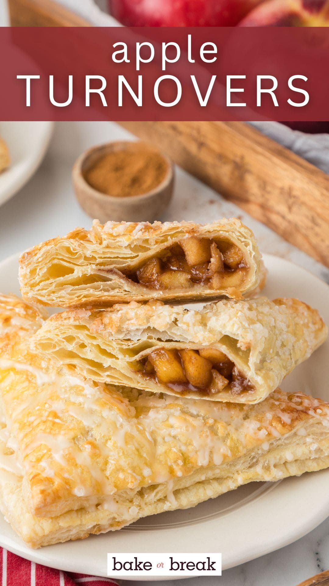 Close-up of a stacked apple turnover sliced in half, revealing cinnamon apple filling and flaky pastry layers