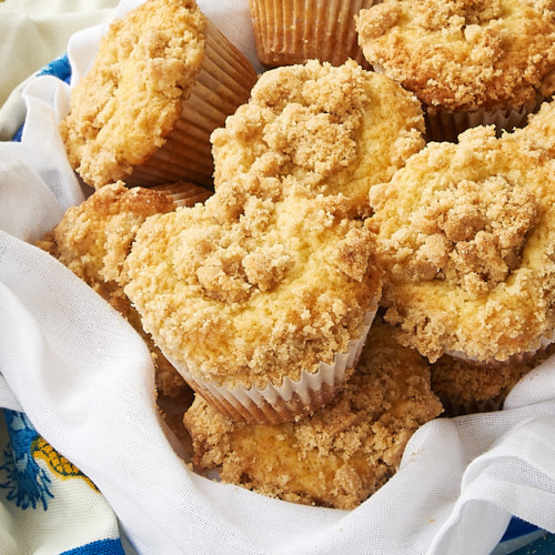 Vanilla crumb muffins in white paper liners on a dark surface