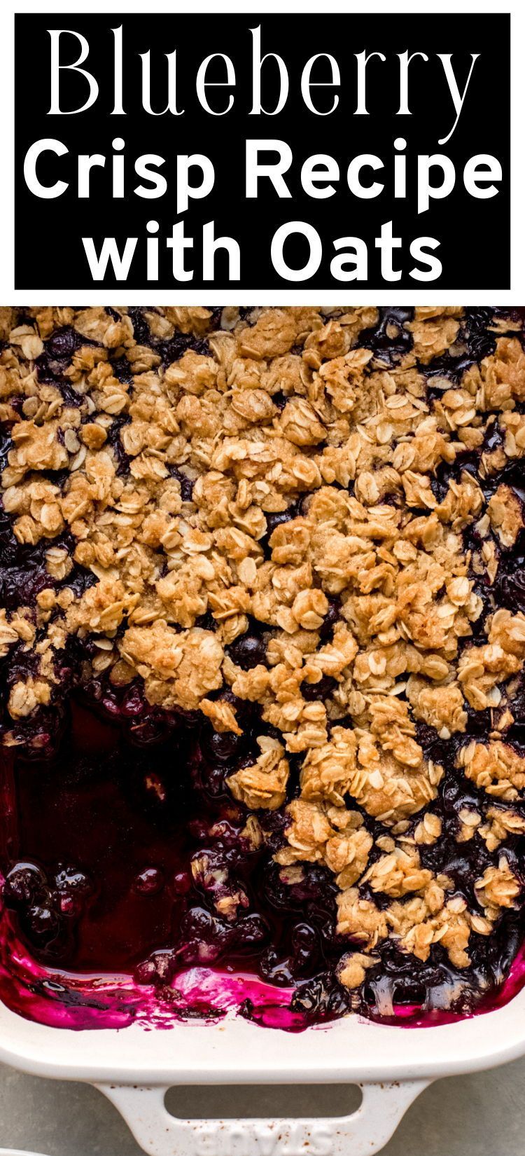 Close-up of baked blueberry crisp with a golden-brown oat topping in a white baking dish.