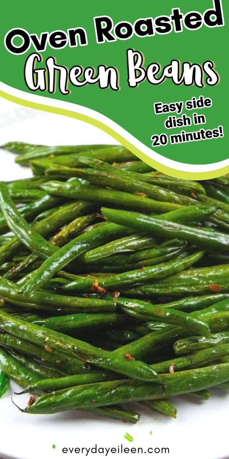 Close-up of a pile of bright green oven-roasted green beans on a white plate, showing some browning and seasoning flecks.