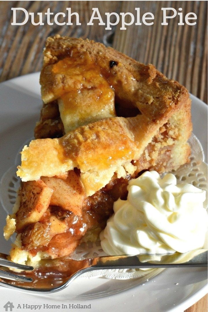 Close-up of a slice of apple pie with a crumb top, served with whipped cream and a fork.