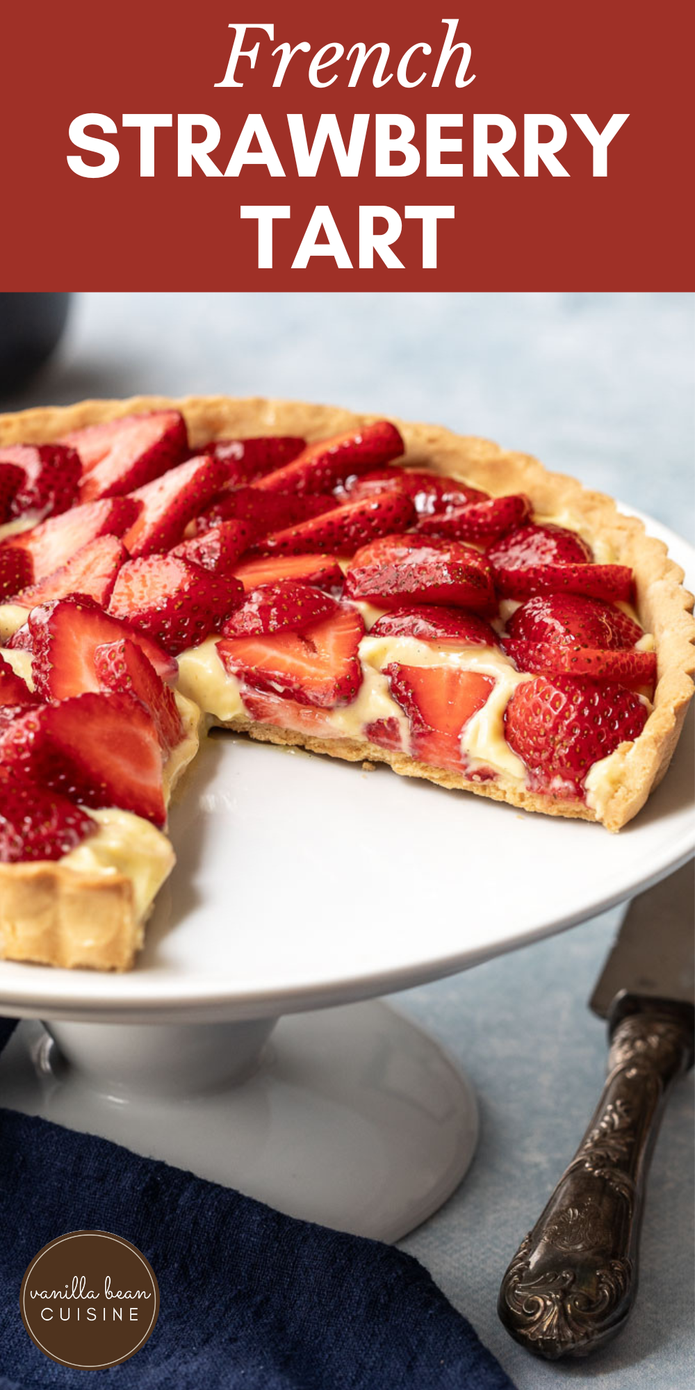 French strawberry tart with one slice removed, on a white cake stand