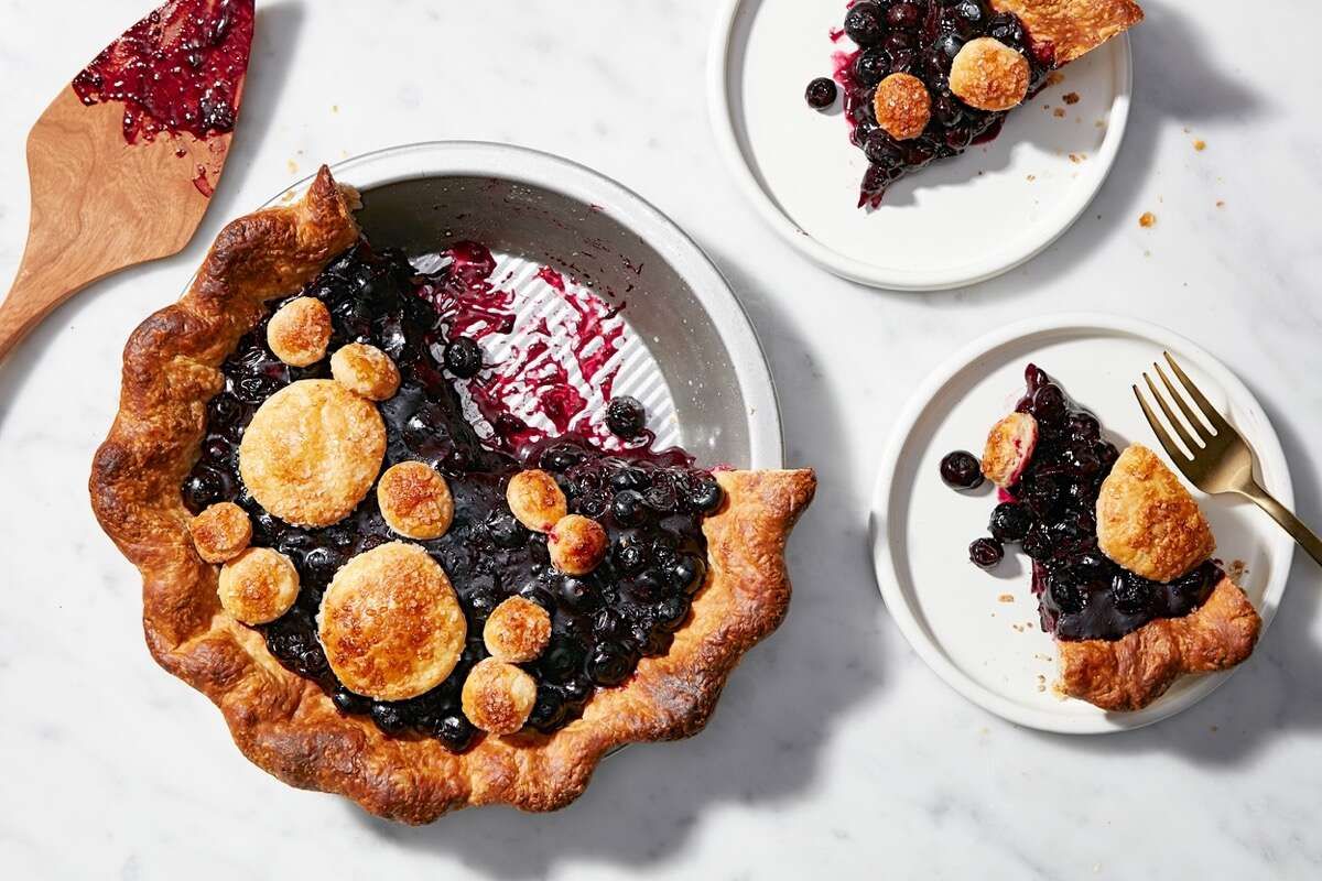 Blueberry tart in a fluted metal pan with two slices removed and on separate white plates