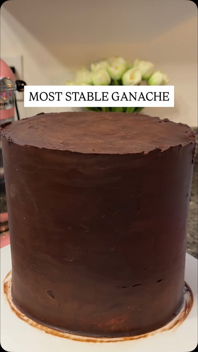 Chocolate ganache-covered cake with smooth sides and top, ready for further decoration or serving.
