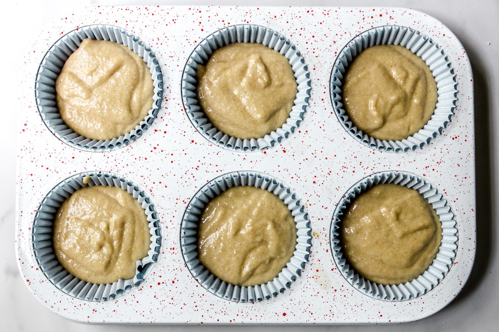 Vanilla muffins with a coarse sugar crumb topping in pale blue paper liners