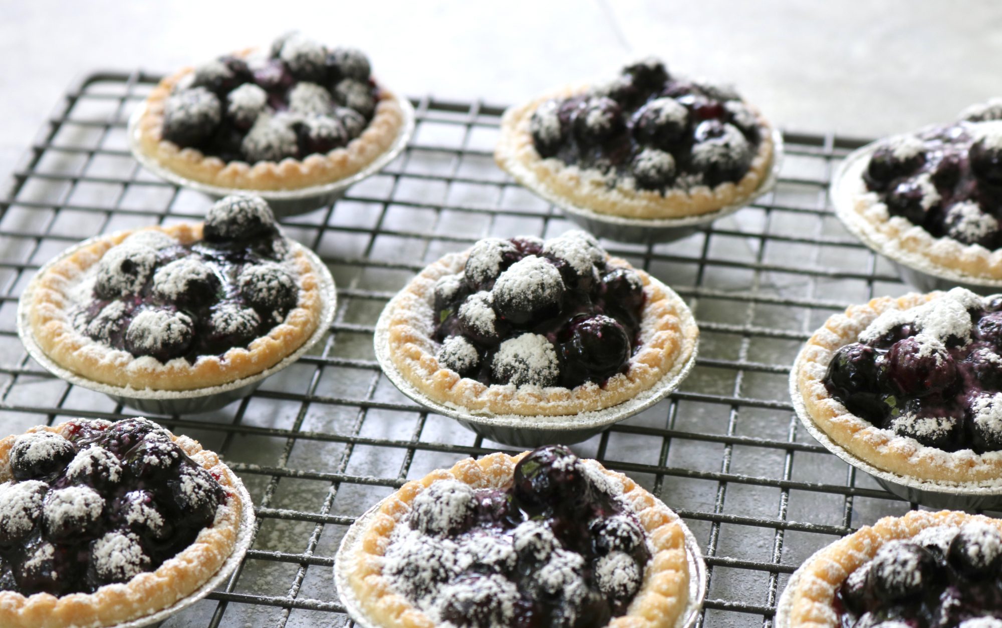 Small berry tarts with dark berry filling in pastry shells.