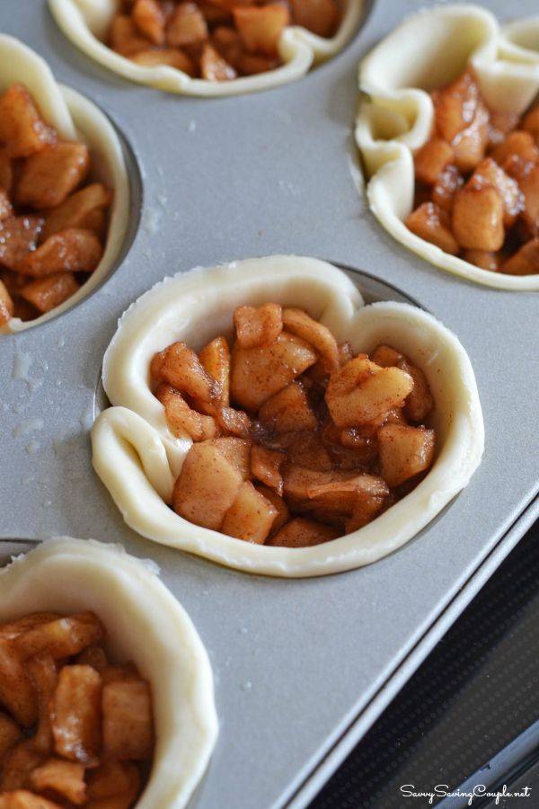 Unbaked mini apple galettes with pie crusts and diced apple filling in a muffin tin.
