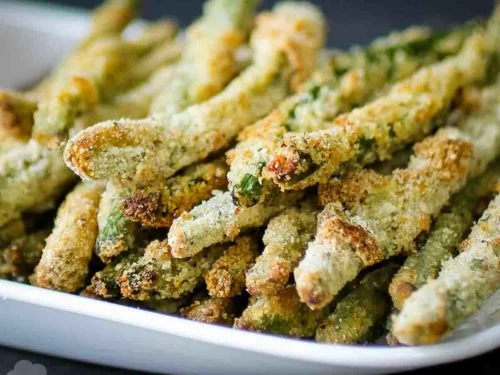 Breaded baked green bean fries on a plate with dipping sauce
