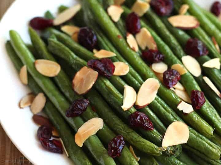 Roasted green beans on a plate with dried cranberries and sliced almonds