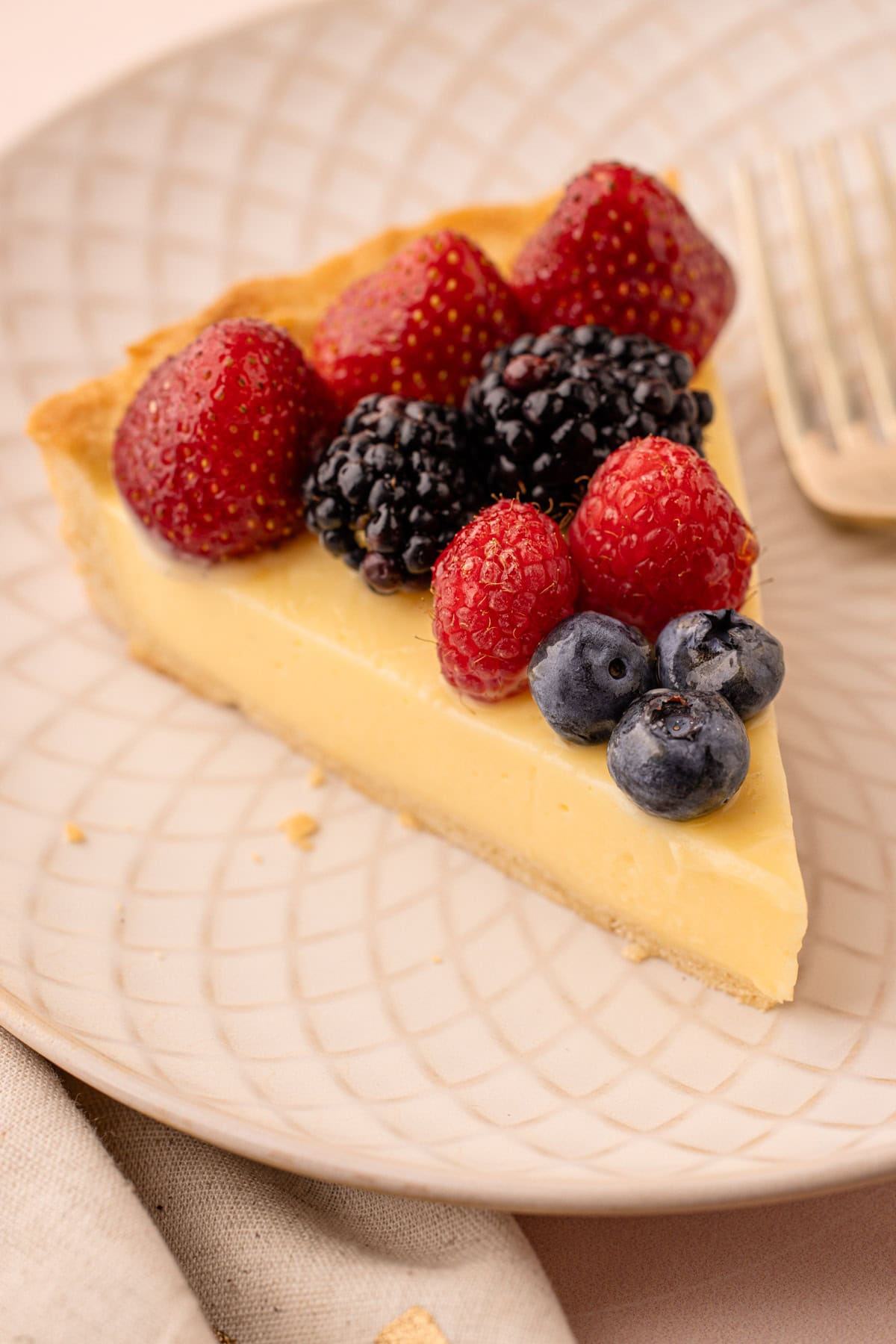 Fruit tart with mixed berries arranged over a pale cream filling.