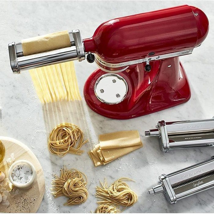 Red stand mixer with a pasta sheet roller attachment extruding fresh pasta.