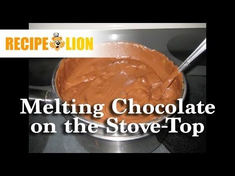 Melted chocolate in a saucepan on a stovetop, being stirred with a spoon.